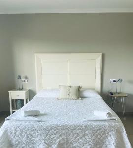 1 dormitorio con 1 cama blanca y 2 toallas en 9 Olas, en A Lanzada