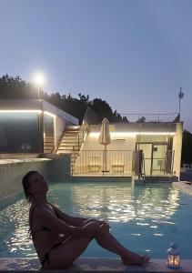 una mujer sentada en el agua en una piscina en La Locanda di Petriolo, en Monticiano