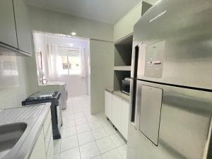 a kitchen with a stainless steel refrigerator and a sink at Apto a 30m da praia sobre shopping Atlântico in Balneário Camboriú +20 photos