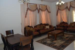 a living room with couches and a table and chairs at RED Bn Breek Villa in Salalah