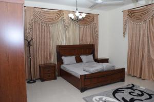 a bedroom with a bed and a lamp and curtains at Red-37 - Bn Breek Villa in Salalah