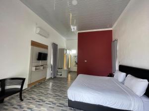 1 dormitorio con cama blanca y pared roja en Pondok Sahang Cottages en Muntok