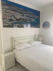 ランペドゥーザにあるラ サリーナの白いベッドと壁に絵画が飾られたベッドルーム1室