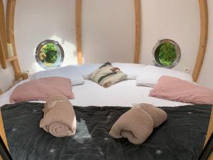 a bed with two moroccan towels on it with two windows at La Ville Es Renais - ferme et maison d'hôtes insolite in Erquy