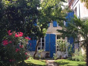 a house with blue doors and flowers in the yard at L’orangerie du Général in Saint-Jean-dʼAngély