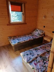 two beds in a room with a window at Agroturystykadomkistawisko in Solina