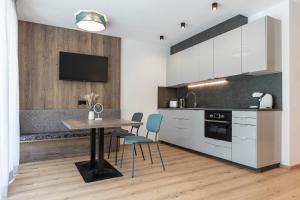 a kitchen with white cabinets and a table and chairs at Bergmadl Apartments in Neustift im Stubaital