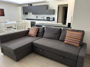 a gray couch in a living room with a kitchen at Casa Anna in Rapolano Terme