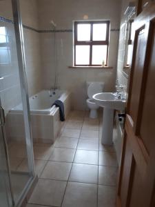 ein Badezimmer mit einer Badewanne, einem WC und einem Waschbecken in der Unterkunft Ballytigue House in Droíchead an Chláir