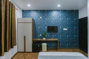 a bedroom with a blue wall with a tv on it at Peony Hotel in Can Tho