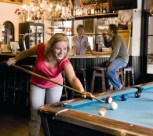 Ein junges Mädchen spielt Billard in einer Bar in der Unterkunft Riant huisje in bosrijke omgeving op chaletpark Kempenbos in Diessen