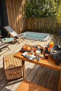 een picknicktafel met eten op een terras met een hot tub bij Bien Loin d'Ici Spa B&B in Nîmes