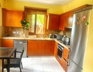 a kitchen with wooden cabinets and a stainless steel refrigerator at Villa Victoria Ayia Napa in Ayia Napa