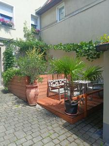 une terrasse en bois avec un banc et des plantes en pot dans l'établissement Main Idyll, à Frickenhausen