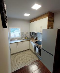 eine Küche mit weißen Schränken und einem weißen Kühlschrank in der Unterkunft Cal Perico, apartamento para turistas y escaladores in Camarasa + 11 Fotos