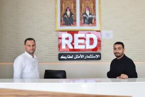 two men sitting at a table with a red sign at RED Royal Inn in Salalah