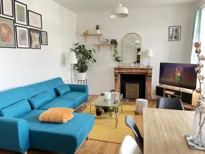 ein Wohnzimmer mit einem blauen Sofa und einem TV in der Unterkunft Cœur de Vendôme in Vendôme
