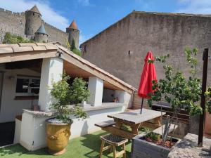 a patio with a table and a red umbrella at La Terrasse du Temps Jadis ConcirgerieDameCarcas in Carcassonne