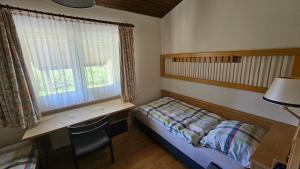 a bedroom with a bed and a desk and a window at Landhaus Wald und See Nr. 35 in Biersdorf