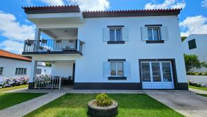 a white house with a balcony and a yard at Moniz House in Santa Cruz da Graciosa