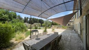un patio al aire libre con mesa y sombrilla en Mas Millésime - Gîte Mourvèdre - 6 pers - Piscine privative - St Remy de Provence, en Mas blanc des Alpilles