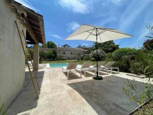 un patio con sillas, una sombrilla y una piscina en Mas Millésime - Gîte Mourvèdre - 6 pers - Piscine privative - St Remy de Provence, en Mas blanc des Alpilles