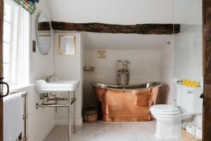 a bathroom with a copper tub and a toilet at Crippens, A historic 5 star Home Hotel Free Parking EV, inglenook fireplace in Canterbury