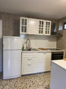 cocina con armarios blancos y nevera blanca en Petite house en Starigrad-Paklenica