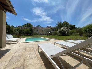 una piscina con 2 tumbonas junto a una casa en Mas Millésime - Gîte Mourvèdre - 6 pers - Piscine privative - St Remy de Provence, en Mas blanc des Alpilles