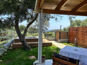 un patio con una mesa y un árbol en Ipsia Apartments, en Paleokastritsa