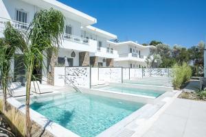 a swimming pool in front of a white house at Anemone Premium Suites Faliraki in Faliraki