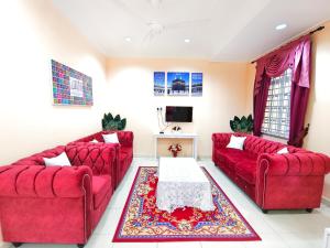 una sala de estar con 2 sofás rojos y una mesa. en Ujana Damai - Cosy 5 bedrooms near UMT UNISZA, en Kuala Terengganu
