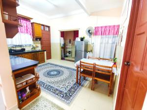 a kitchen with a table and a refrigerator at Ujana Damai - Cosy 5 bedrooms near UMT UNISZA in Kuala Terengganu
