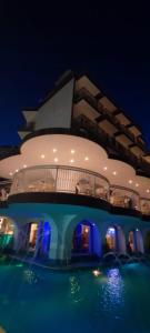 a building with a swimming pool at night at Hotel B&B Negresco in Milano Marittima