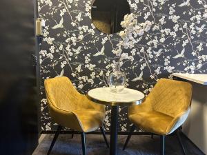 a table and two chairs in front of a wall with flowers at Privespa hotel Little escape in Wormer