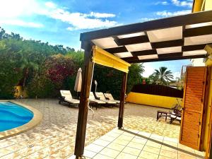 une terrasse avec des chaises et un parasol ainsi qu'une piscine dans l'établissement Villa Victoria Ayia Napa, à Ayia Napa