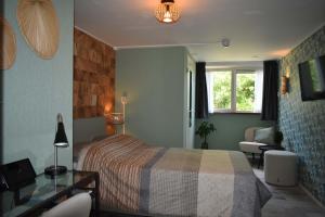 a bedroom with a bed and a desk and a window at Hotel Dichtbijzee in Oosterend