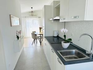 eine weiße Küche mit einem Waschbecken und einem Tisch in der Unterkunft Apartments Babić in Trogir