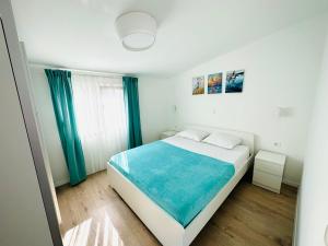 a white bedroom with a bed and a window at Apartments Babić in Trogir