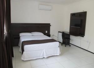 a bedroom with a bed and a flat screen tv at SP Hotel Fortaleza in Fortaleza