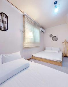 1 Schlafzimmer mit 2 Betten und einem Fenster in der Unterkunft Blau Guesthouse in Gyeongju
