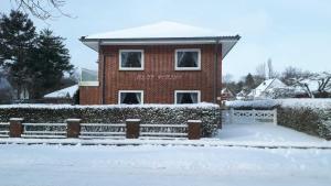 une maison en briques dans la neige avec une clôture dans l'établissement Haus Wiking, à Wyk auf Föhr