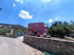 a pink house with cars parked on the side of a road at Little pomegranate apartment in Kapótidhes