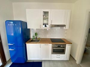 una pequeña cocina con armarios blancos y nevera azul en COSTA PARADISO BELVEDERE APPARTAMENTO Vista Mare, en Costa Paradiso