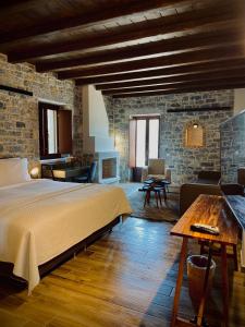 a bedroom with a large bed and a stone wall at Manifest Boutique Hotel in Oitylo