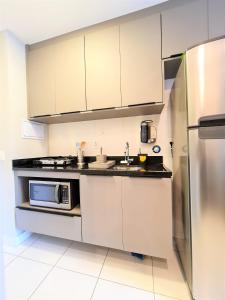 a kitchen with a microwave and a refrigerator at Studio Benê em Pinheiros. in Sao Paulo