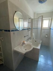 Baño blanco con lavabo y espejo en Apartments Šimić, en Trogir