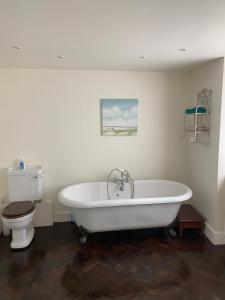 a bathroom with a white tub and a toilet at Bluebell Barn in Banham