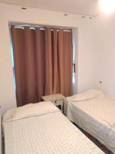 two twin beds in a room with a curtain at Habitaciones playa de Gandía in Playa de Gandia