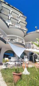 a building with white chairs and a building with balconies at Hotel B&B Negresco in Milano Marittima